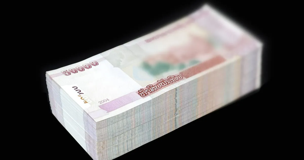 Une liasse de billets empilée sur un fond sombre